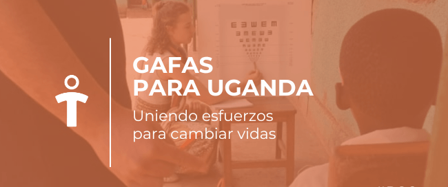 Niño recibiendo gafas de un voluntario en una clínica de Uganda, con un cartel de prueba de visión al fondo